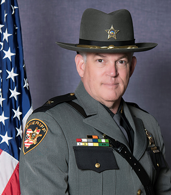Sheriff Lape, posed in front of American flag