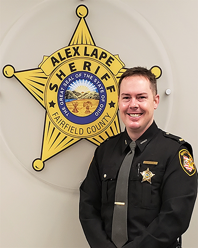 officer standing next to sheriff logo